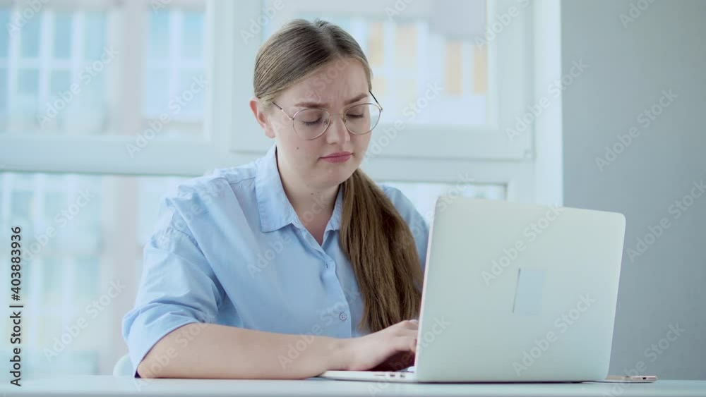 Tired woman in eyeglasses with ponytail working on laptop, problems with program Tired woman in eyeglasses with ponytail working on laptop, problems with program