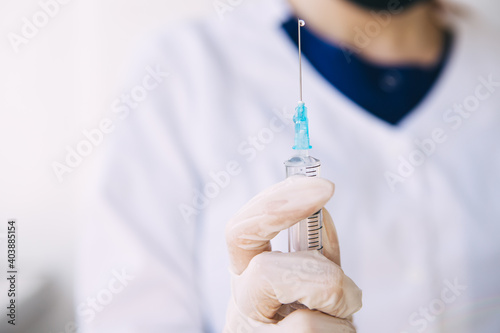 young doctor is holding a syringe of medicine. Coronavirus vaccine in a syringe. Cope space.