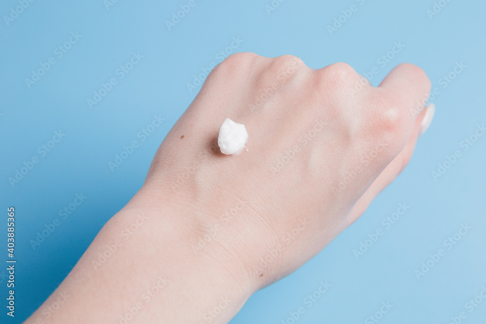 drop of white body cream on the girl's hand on a blue background drop of white body cream on the girl's hand on a blue background