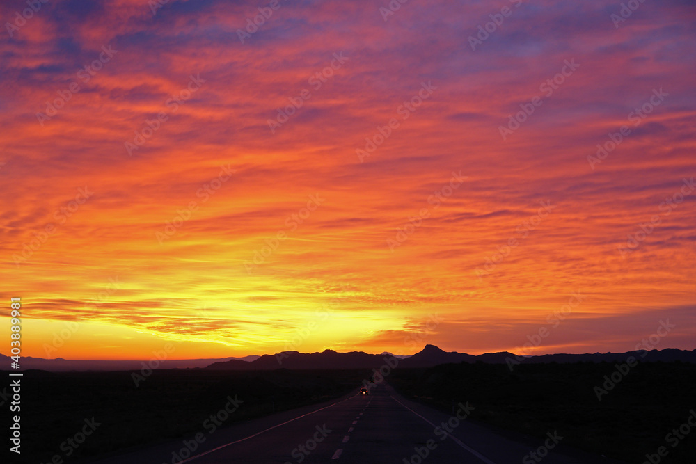Obraz premium beautiful sun rising sky with asphalt road and cars going toward mountains in horizon