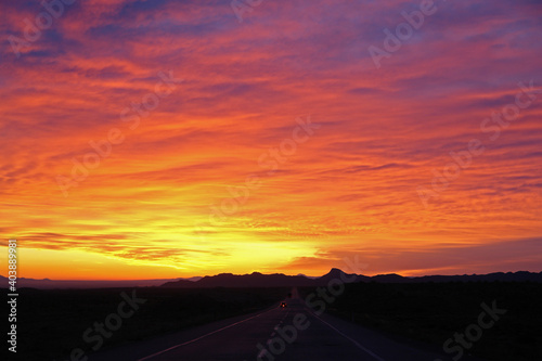 beautiful sun rising sky with asphalt road and cars going toward mountains in horizon