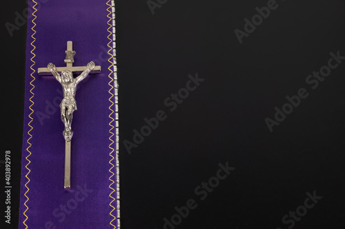 Purple violet priest's stole with a metal cross on a black background