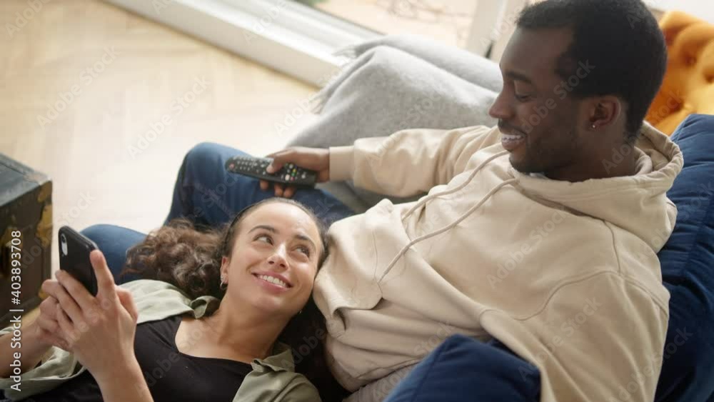 Overhead Shot Of Relaxed Young Couple At Home On Sofa Watching TV And Checking Mobile Phone Overhead Shot Of Relaxed Young Couple At Home On Sofa Watching TV And Checking Mobile Phone