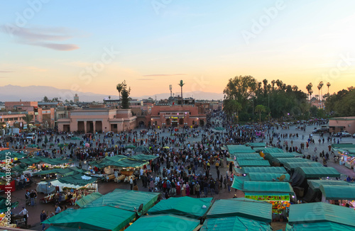 Hectic life in Jemal el Fna square with green market stalls at dusk