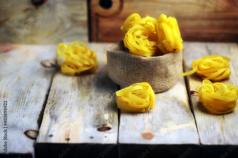 Raw fetuccine pasta on a wooden surface. Nest paste. Italian Cuisine. Selective focus.