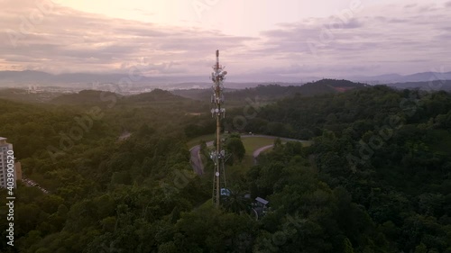 4K UHD Cinematic Aerial footage circle view of 5G Communication tower during morning sunrise with clouds, mists and fog