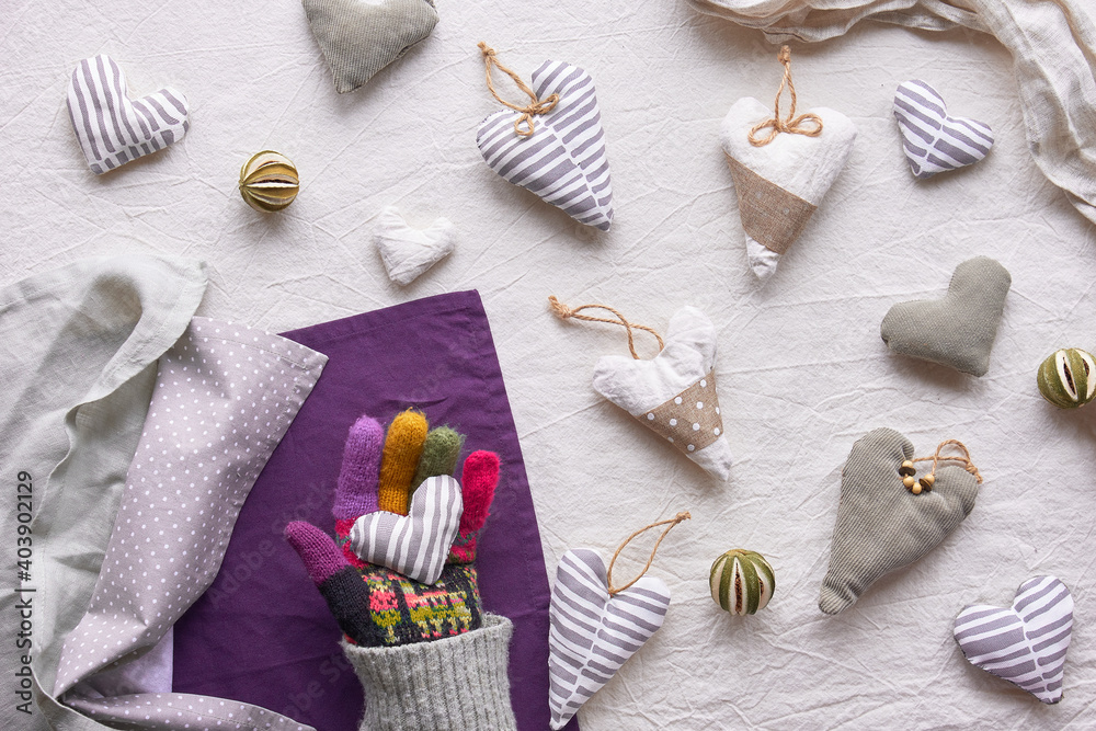 Hand made textile hearts and balls on cotton background. Textile stuffed toys, balls and candle in neutral colors and purple color. Flat grey winter window light. Hand made textile hearts and balls on cotton background. Textile stuffed toys, balls and candle in neutral colors and purple color. Flat grey winter window light.