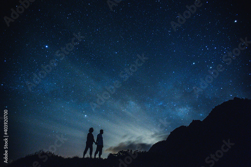 Silhouette of elderly couple on the hill. Stargazing at Oahu island, Hawaii. Starry night sky, Milky Way galaxy astrophotography.