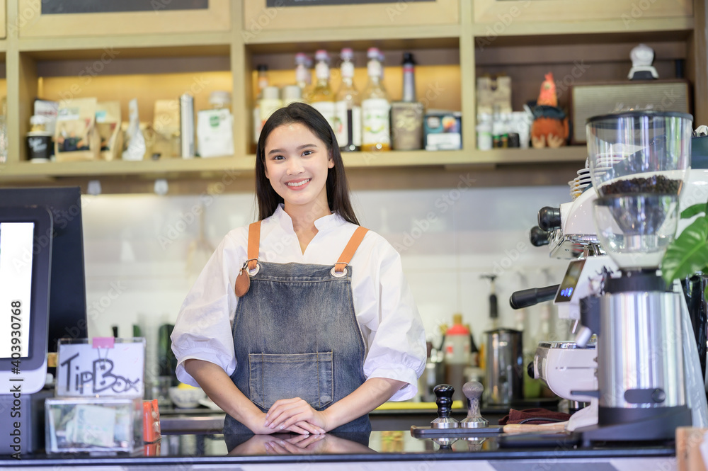 Asian women Barista smiling and using coffee machine in coffee shop counter