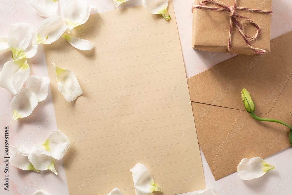 Gift box and letter next to beautiful white flowers on pink marble background