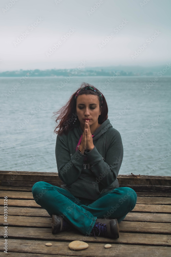 young woman meditating in front of the sea