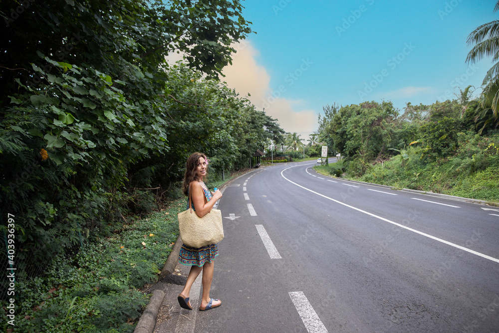 Woman walking on main road in tropical island Moorea in French Polynesia Woman walking on main road in tropical island Moorea in French Polynesia