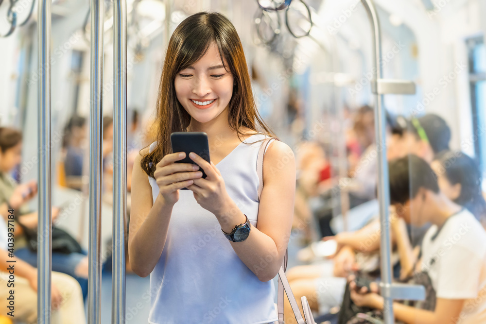 Young Asian woman passenger using social network via smart mobile phone in subway train when traveling in big city,japanese,chinese,Korean lifestyle and daily life, commuter and transportation concept