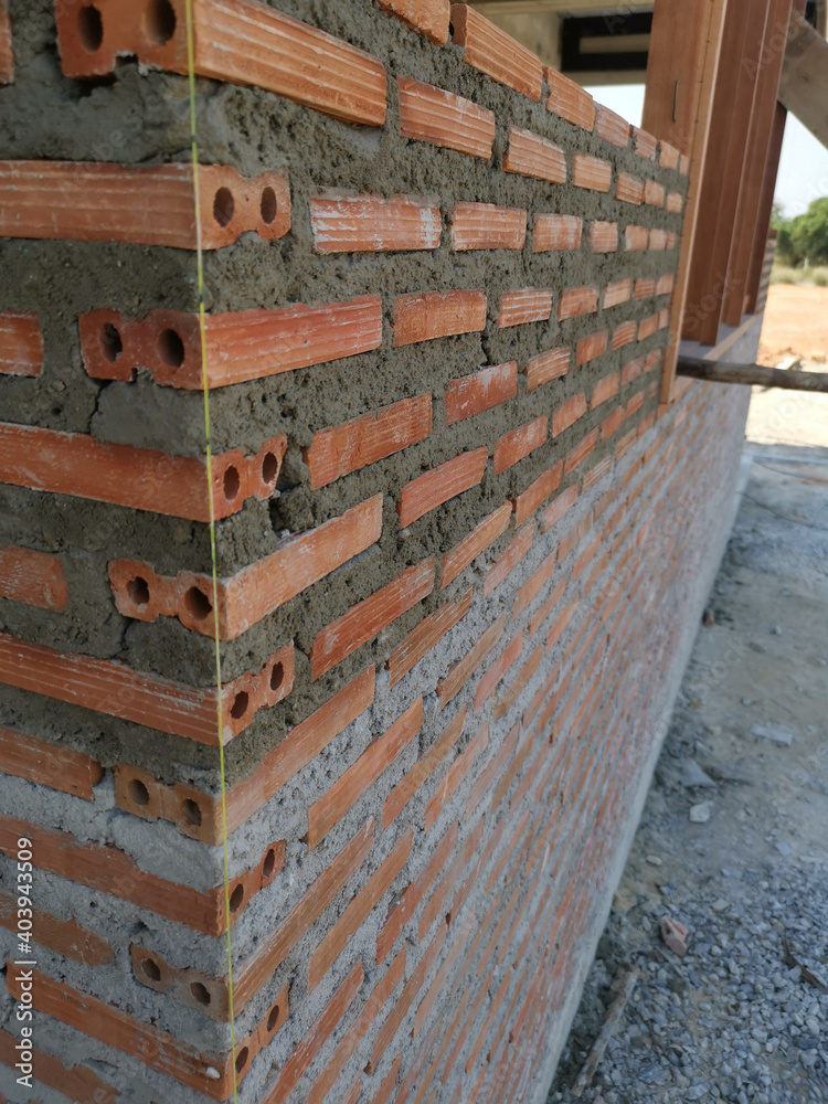 A new red brick wall. The dry mortar is layered in two colors. The bare walls are not plastered on the surface. A new red brick wall. The dry mortar is layered in two colors. The bare walls are not plastered on the surface.