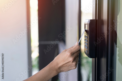 young woman using RFID tag key card, fingerprint and access control to open the door in a office building