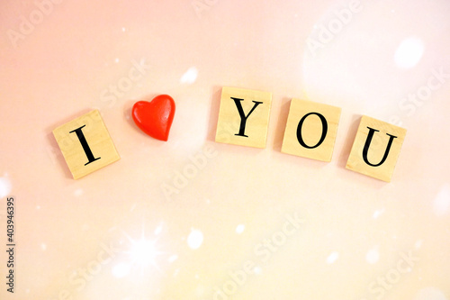 Wood block alphabet I love You with red heart on pink bokeh and light background. 