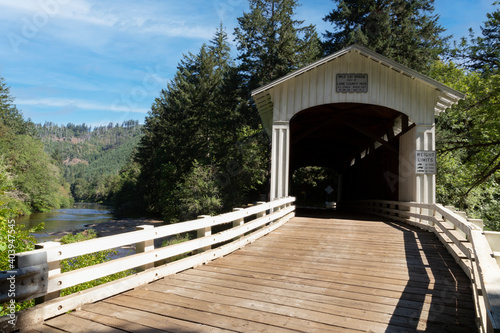 Wild Cat covered bridge with green lush trees in a rural area of Oregon - A sunlit, right side of frame perspective 