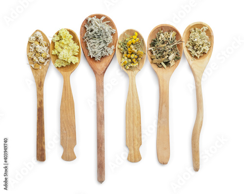 Spoons with different herbs on white background