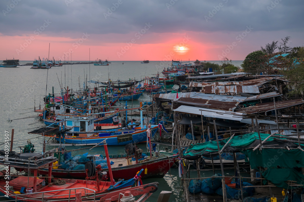Fishing boat and village at sunrise in Cha-Am