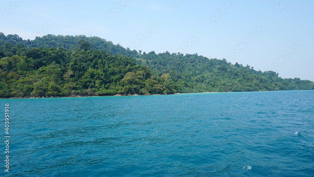 Fototapeta premium Travel by sea in Thailand by ship. View of the open ocean, green Islands and gray sky in smog. Green water with waves. Sailing between the Islands. Ship from different sides: stern, bow, rope, anchor.