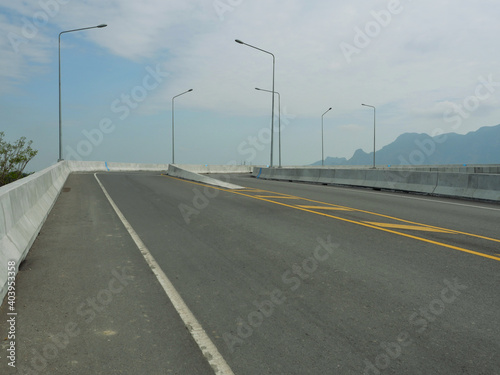 Open road on the bridge with mountain and blue sky in background, Southeast Asia, Thailand