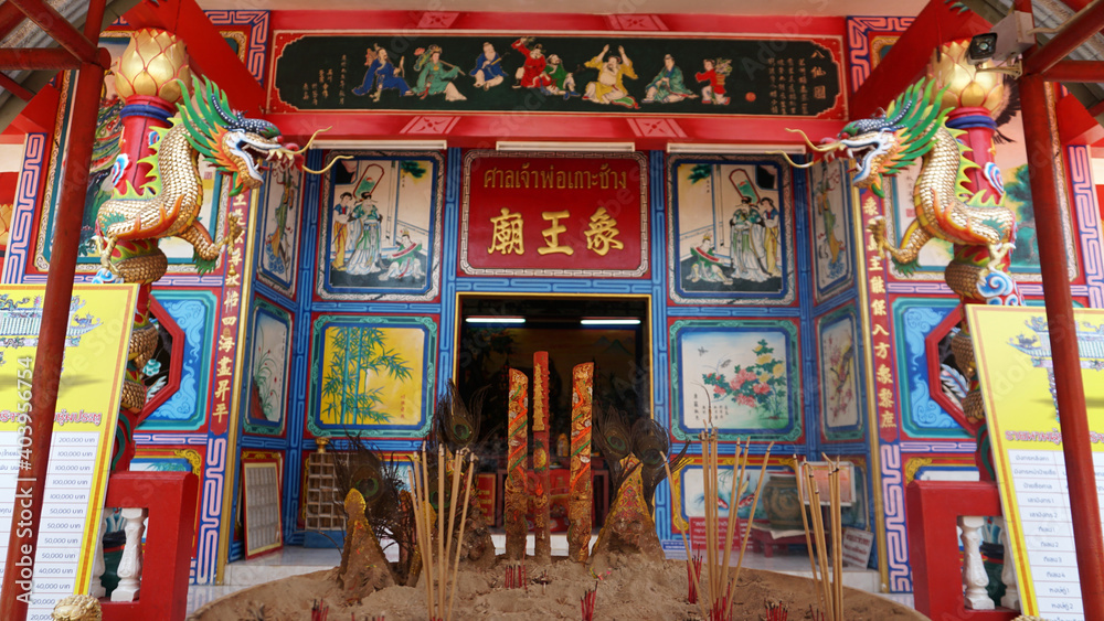 Chinese temple on Koh Chang island of Thailand. Bright colors of the temple, dragon and elephant sculptures. Flowers all around. The smoke from the sticks is coming. Hieroglyphs on the walls of bell.