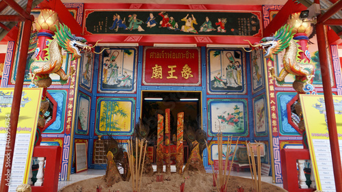 Chinese temple on Koh Chang island of Thailand. Bright colors of the temple, dragon and elephant sculptures. Flowers all around. The smoke from the sticks is coming. Hieroglyphs on the walls of bell.