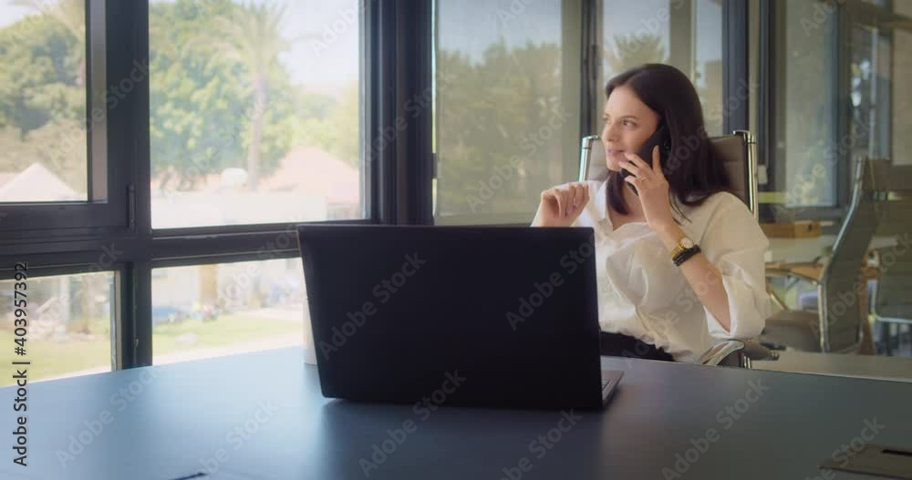 A businesswoman in white blouse talking on the phone, while working at the office. A businesswoman in white blouse talking on the phone, while working at the office.
