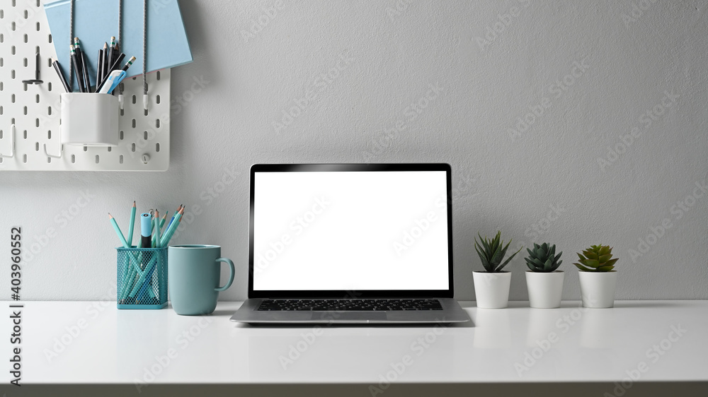 Obraz premium Stylish workstation with laptop computer, stationery, coffee cup and house plant on white table.