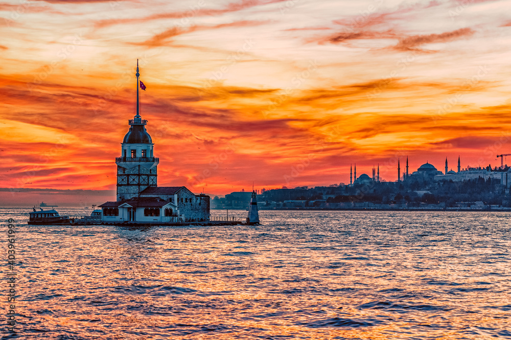 A deep orange sunset paints the sky behind the Maidens Tower in Istanbul Turkey.