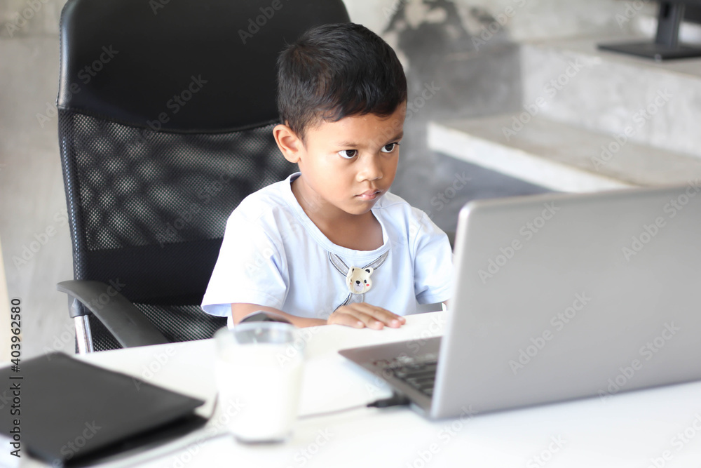 Asian boy kid sitting at table with laptop and preparing to school. Online education concept. Online video call conference class lesson study.