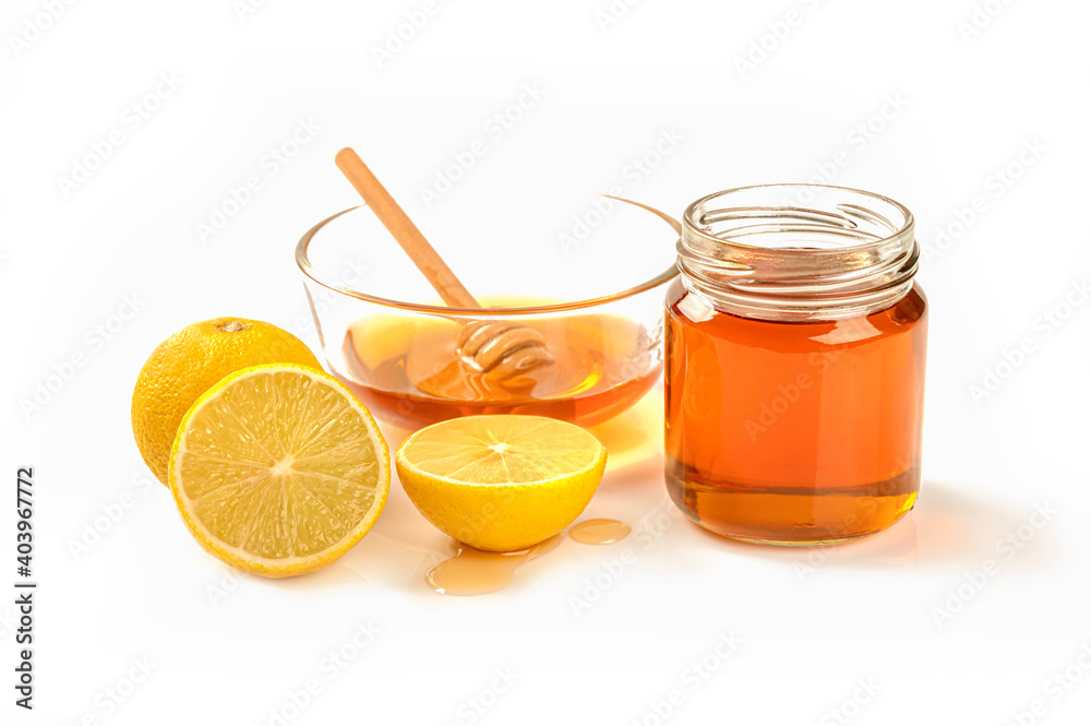 Close up Glass bowl of pure honey with honey bottle honey dipper and lime on white background. Close up Glass bowl of pure honey with honey bottle honey dipper and lime on white background.