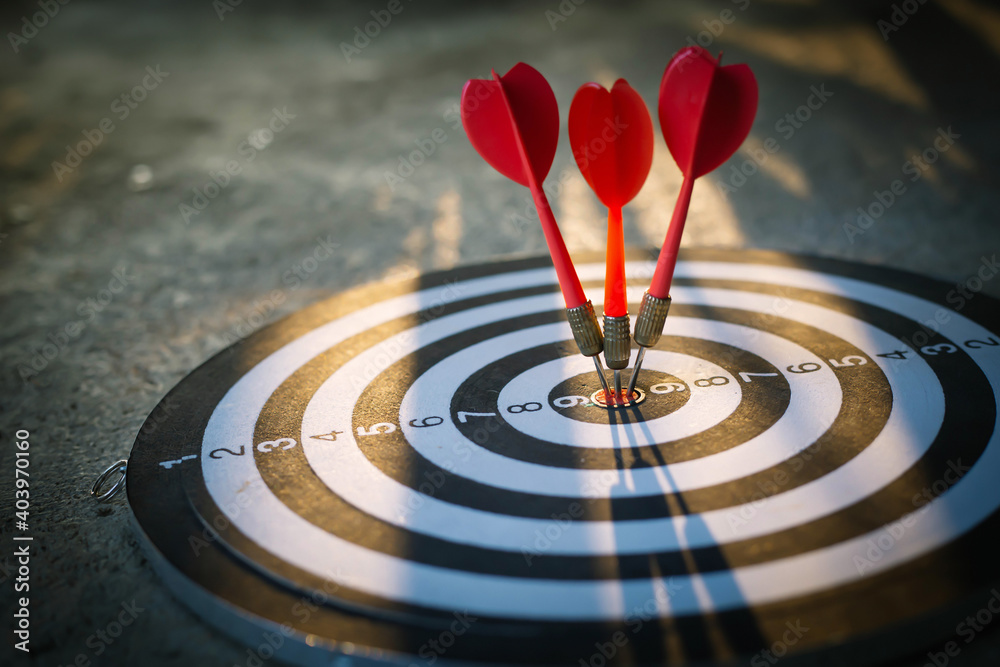 Close up shot of the dart arrow hit on bulleyes of dartboard to represent that the business reached the target with dark tone picture style. Target and goal as concept. Close up shot of the dart arrow hit on bulleyes of dartboard to represent that the business reached the target with dark tone picture style. Target and goal as concept.