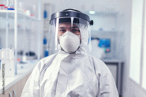 Biochemistry scientist wearing face mask and face shield as safety precaution for covid19 outbreak working in lab. Overworked researcher dressed in protective suit against invection with coronavirus photo