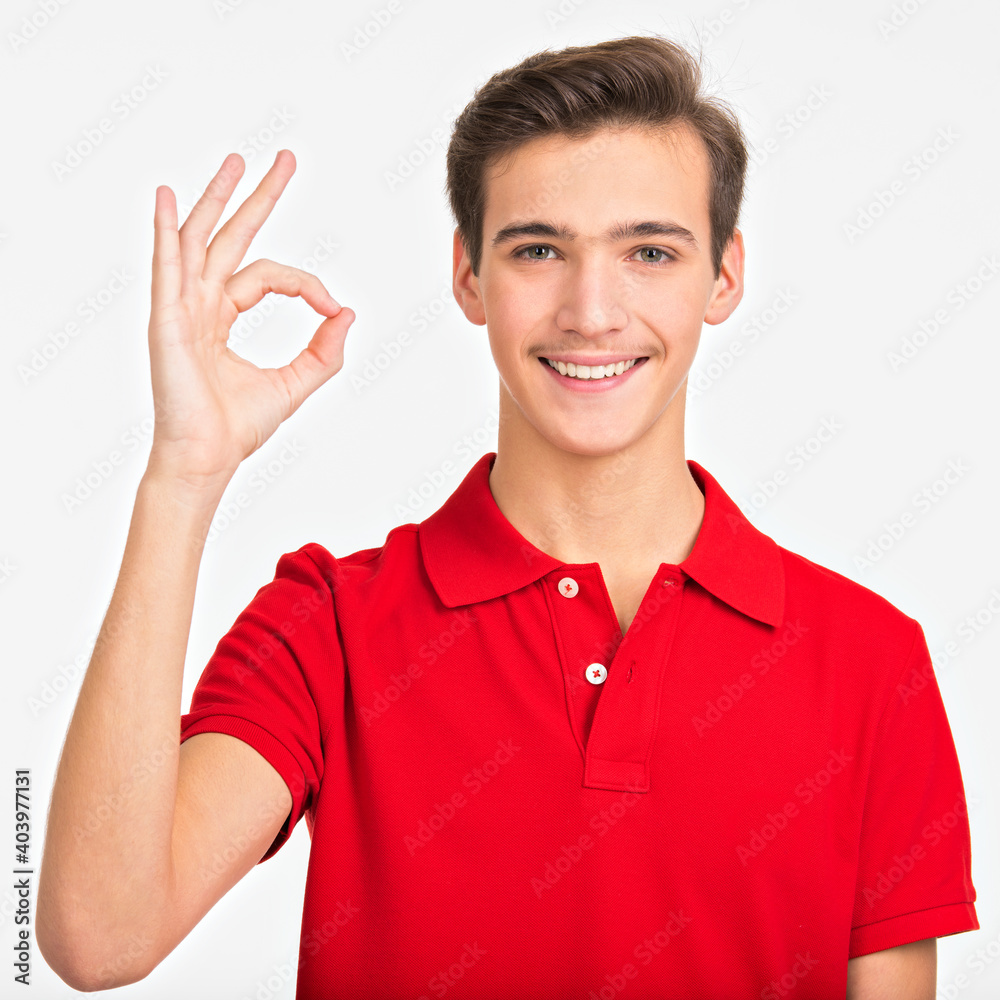 Portrait of happy young man showing okay gesture, isolated over white background. Photo of smiling Handsome white guy in a red shirt with sign OK. Positive Male person shows gesture OKAY . Portrait of happy young man showing okay gesture, isolated over white background. Photo of smiling Handsome white guy in a red shirt with sign OK. Positive Male person shows gesture OKAY .