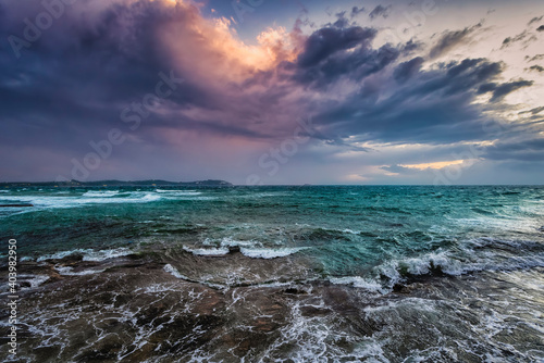 A storm approaching with dark clouds over rough and wavey sea during sunset time
