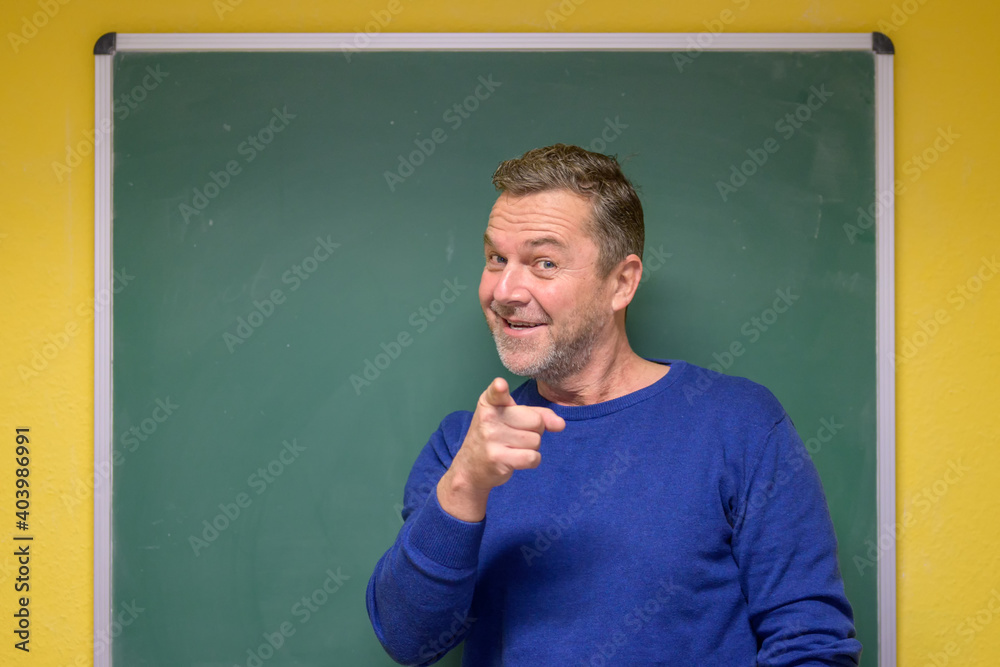 Motivated male teacher pointing at the viewer