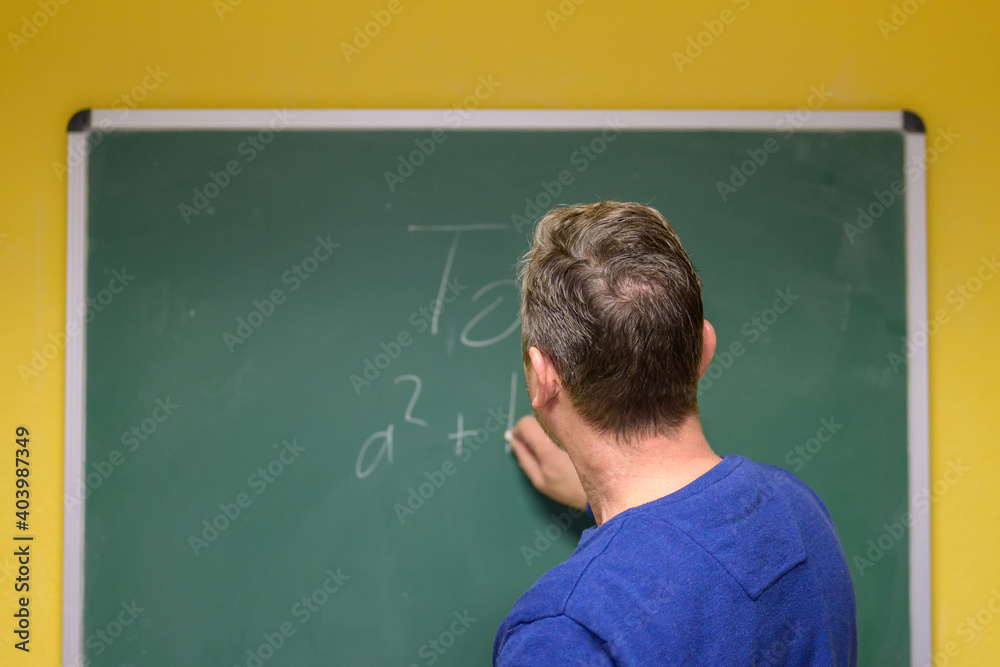 Mathematics teacher writing formula on chalkboard Mathematics teacher writing formula on chalkboard