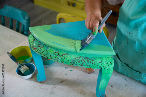 Woman doing art and craft hobby and painting old furniture