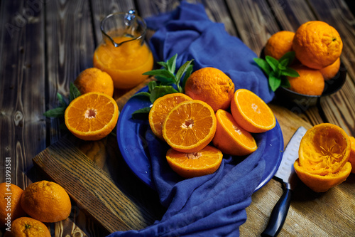 fresh orange juice and oranges with mint on the table with blue cloth and knife 