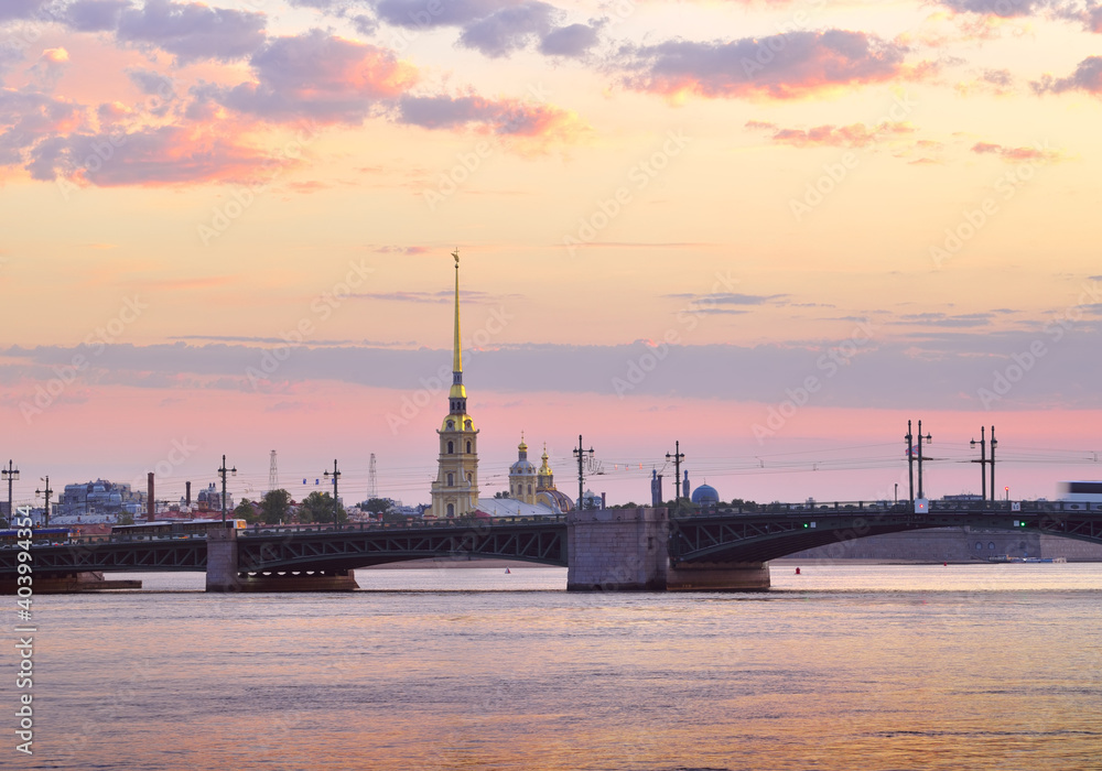 View of Peter and Paul Cathedral at dawn. Palace bridge on the background of pink dawn sky with clouds. Architecture of the XVIII century View of Peter and Paul Cathedral at dawn. Palace bridge on the background of pink dawn sky with clouds. Architecture of the XVIII century