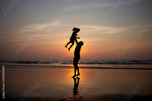 Bringing back good memories.

Silhouette of father and daughter playing on beach during sunset. 