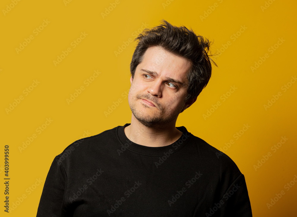 Obraz premium Surprised white guy in black shirt on yellow background
