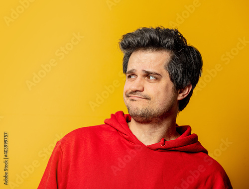 Surprsied guy in red sweatshirt on yellow background photo