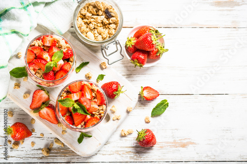 Greek yogurt with fresh strawberry and granola. Parfait in the glass jars. Top view with ingredients.