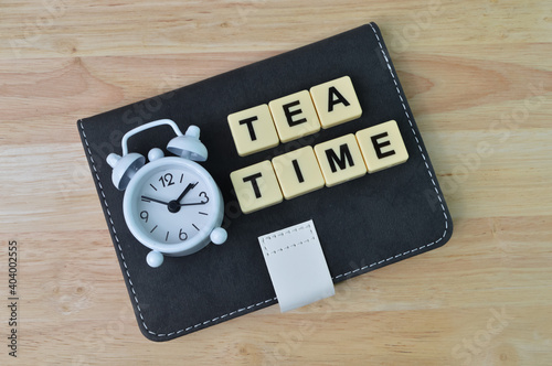 Selective focus of clock, notebook and alphabet letters with text TEA TIME.