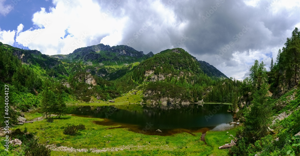 clear dark mountain lake in a green valley with mountains panorama