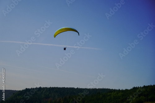 single blue yellow paraglider on the blue sky