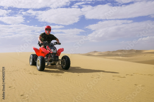 man driving a red quad through the dunes of namibia