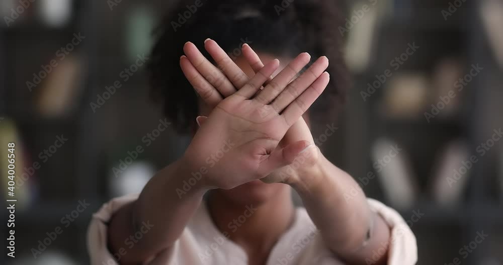 African woman raising folded palms to camera makes defensive hands gesture close up. Female struggle against domestic violence and abuse, social issues, citizen position, against vaccination concept
